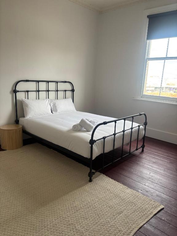 Un dormitorio con una cama con sábanas blancas y una ventana. en Echuca Hotel, en Echuca