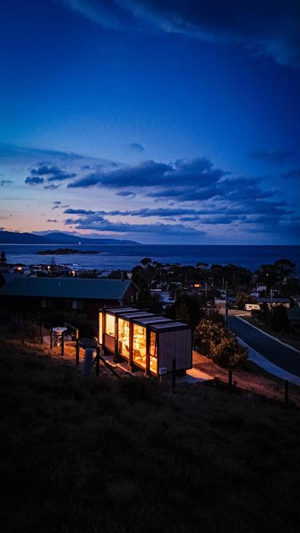 a small building sitting on top of a field at night at The Bambino - By Casa Bicheno in Bicheno