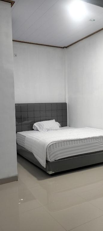 a bedroom with a bed in a white room at Champrink Surfcamp in Wainapal