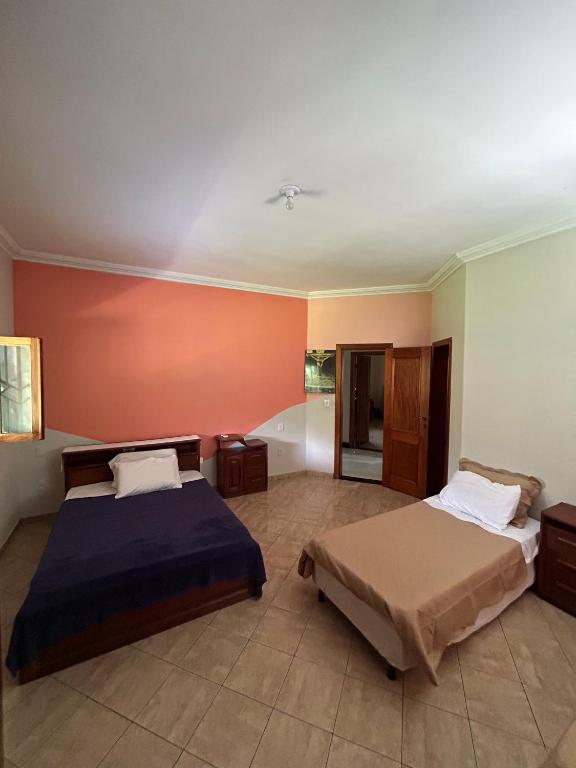 two beds in a room with orange walls at COP30 house in Ananindeua