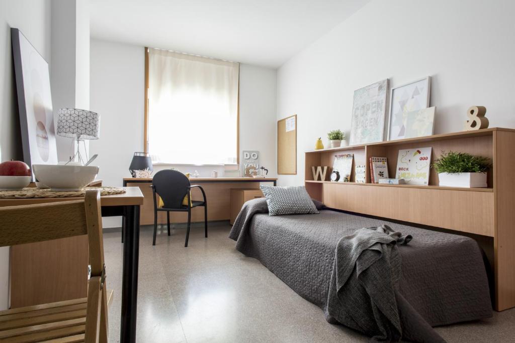 Un dormitorio con una cama y un escritorio y un escritorio. en Residencia Universitaria Resa Campus de Montilivi, en Girona