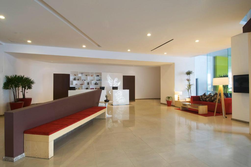A spacious lobby centers on a long red-cushioned bench facing the reception area.