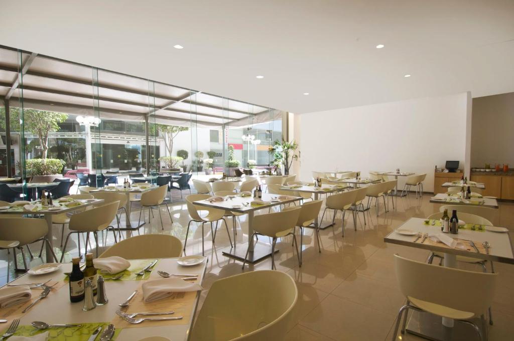 A spacious dining room with large windows is set for service.