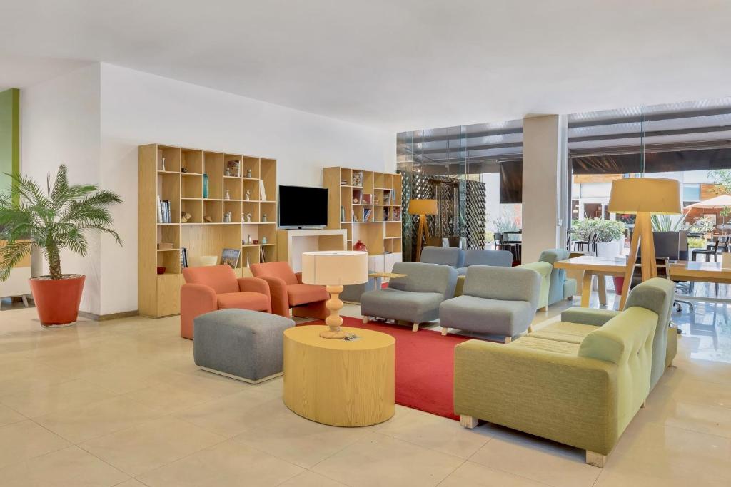 A colorful hotel lobby lounge arranged around low tables and a television.