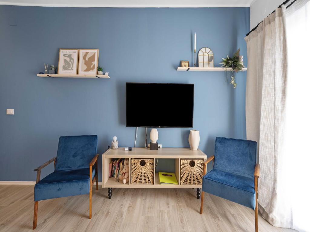 a living room with two blue chairs and a television at One-Bedroom Apartment With Pool in Brodarica