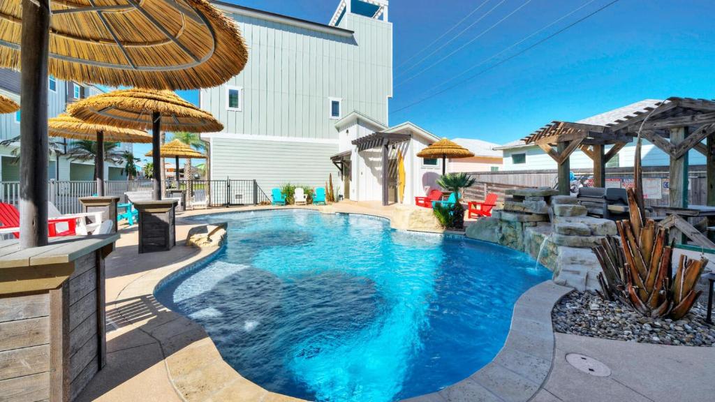 una piscina con agua azul y sombrillas en Resort Pool Walk to the Beach Island Views Little Beach House by AvantStay, en Port Aransas