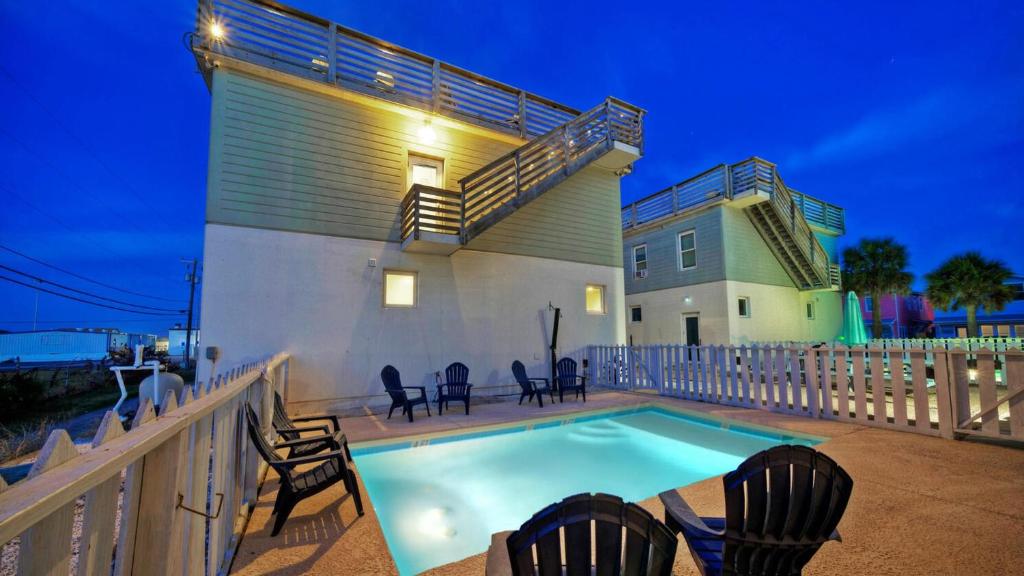 a swimming pool with chairs and a house at Stella Maris by AvantStay Rooftop View Pool in Port Aransas