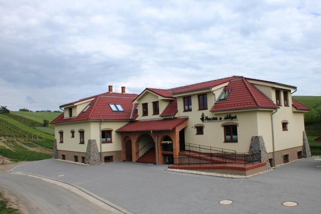 une grande maison avec un toit rouge sur une route dans l'établissement Penzion u sklepů, à Hovorany