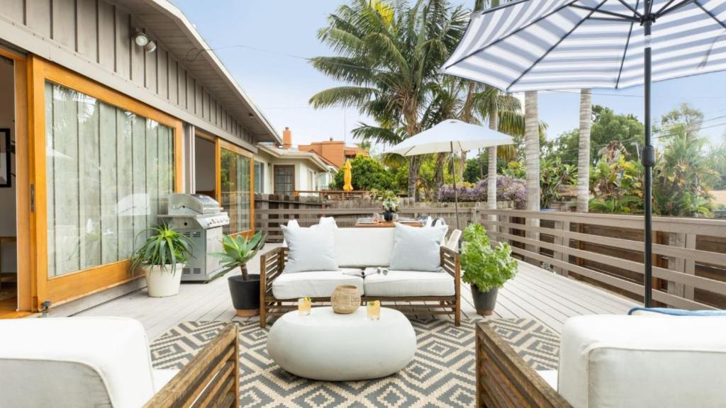 a patio with white furniture and an umbrella at Camden by AvantStay 5mins to the Beach Elevated Home w Pacific Ocean Views in Encinitas