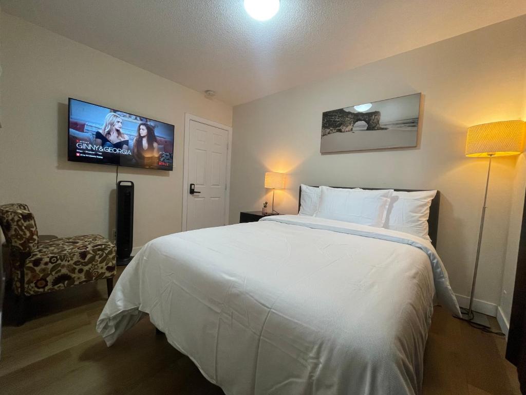 a bedroom with a white bed and a flat screen tv at Lumi Deluxe in Saskatoon