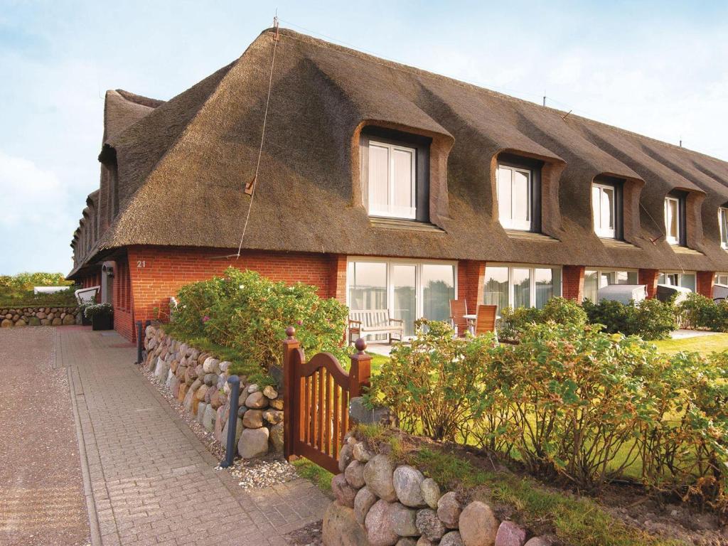 a house with a thatched roof and a fence at Kampbarg-36 in Kampen