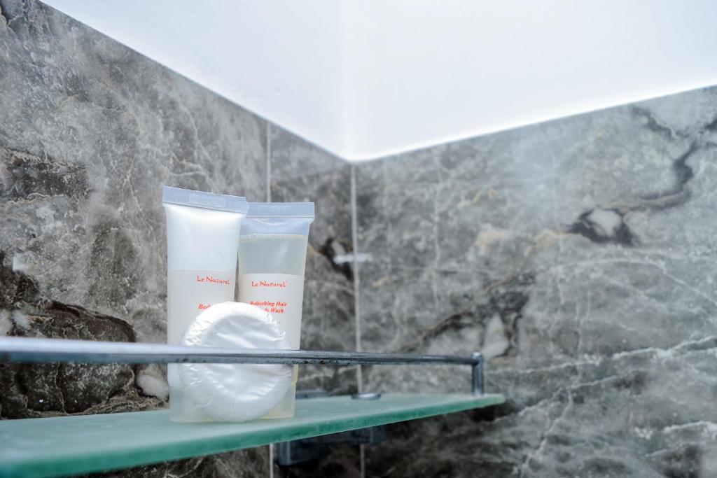 a shelf in a bathroom with two bottles of cream at Ella Bungalow in Ella