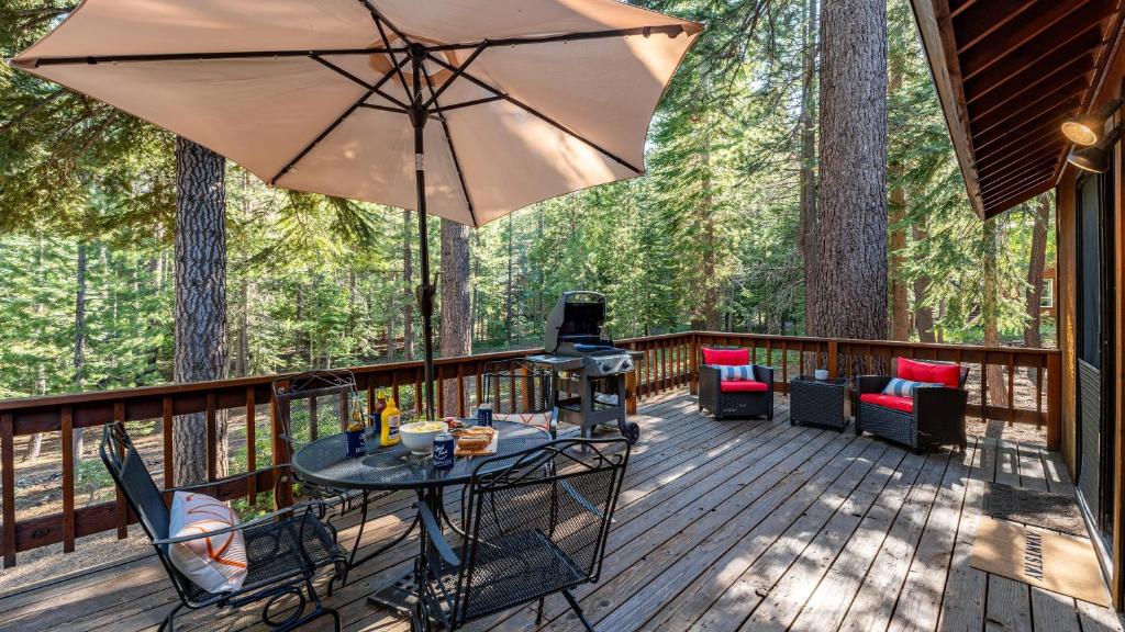 a deck with a table and an umbrella at Whiskey Springs by AvantStay Classic Cabin Near Tahoe Donner Ski Area in Truckee
