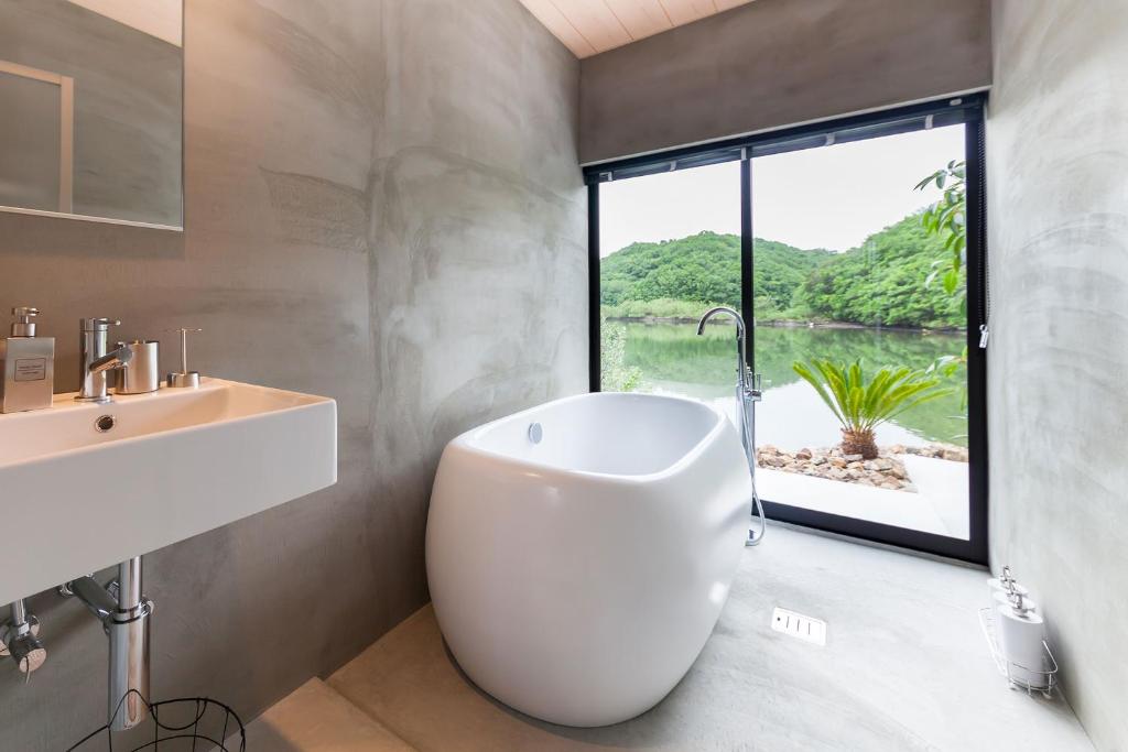 a bathroom with a white tub and a sink and a window at mg-mgream- in Shima