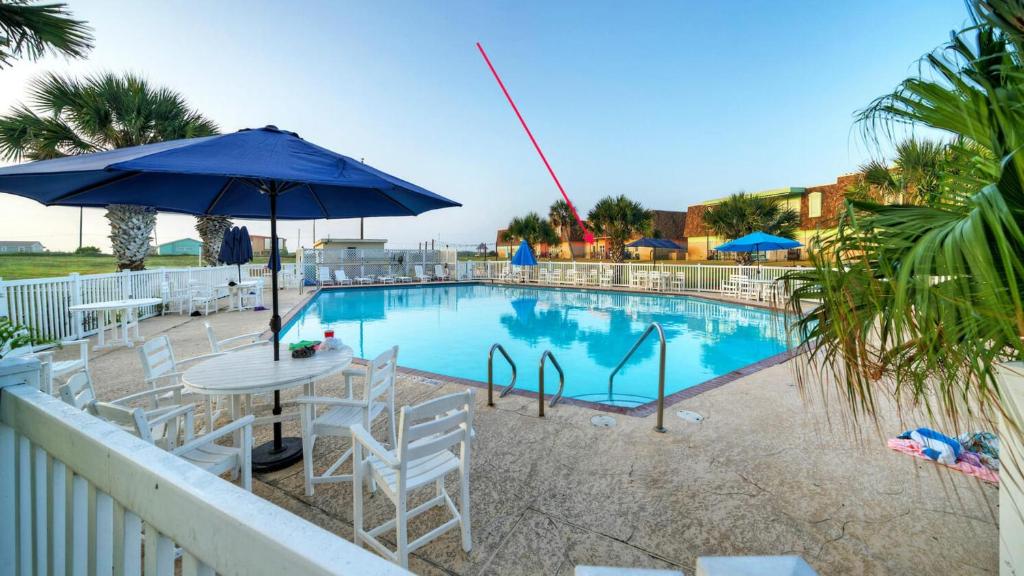 una piscina con sillas, una mesa y una sombrilla en Port A Escape w Pools Patio Walk to Beach La Concha by AvantStay, en Port Aransas