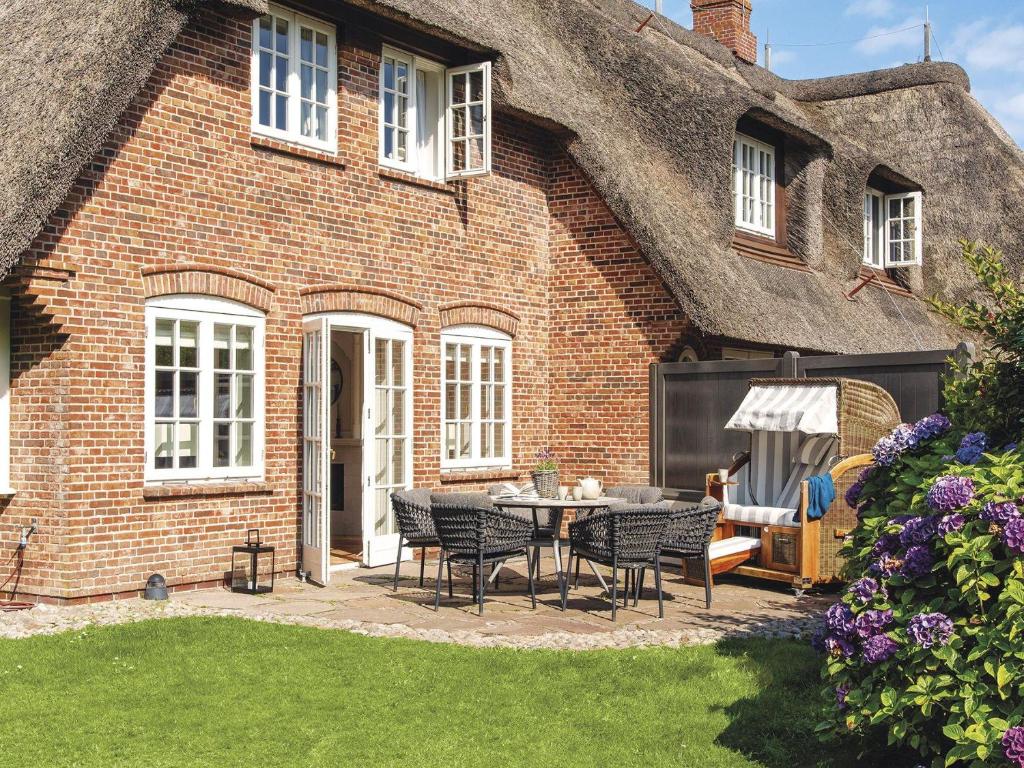 a thatched house with a patio with chairs and a table at Hansenhoog-4 in Kampen