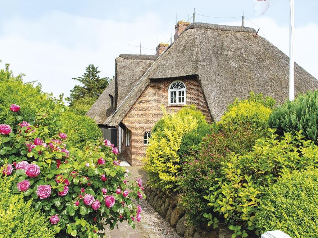 an old house with a thatched roof and pink roses at Hansenhoog-3 in Kampen