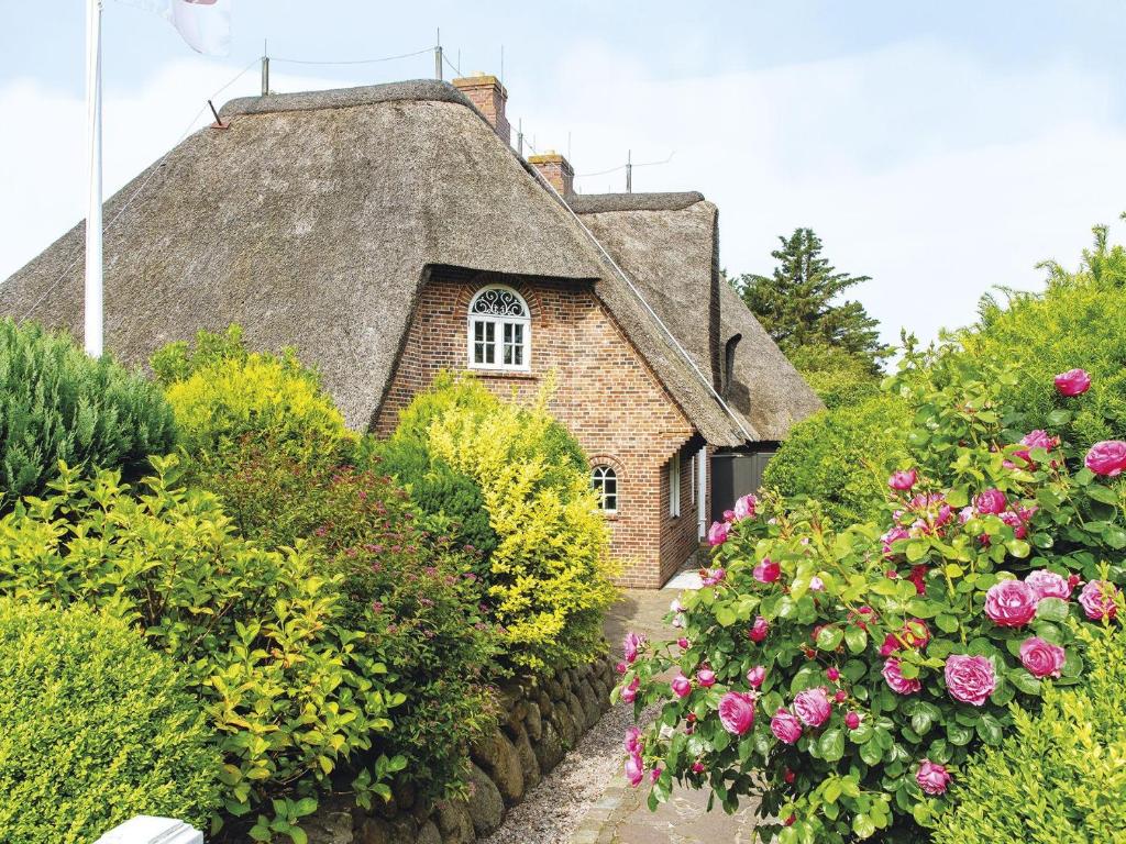 an old house with a thatched roof and flowers at Hansenhoog-2 in Kampen