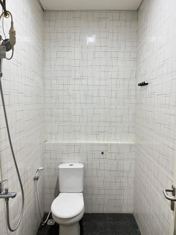 a white bathroom with a toilet and a shower at Alya Villa Syariah in Sidoarjo