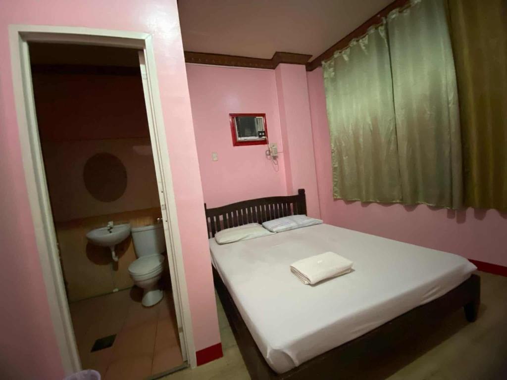 a small bedroom with a bed and a toilet at Wjv Inn Tabunok ll in Talisay