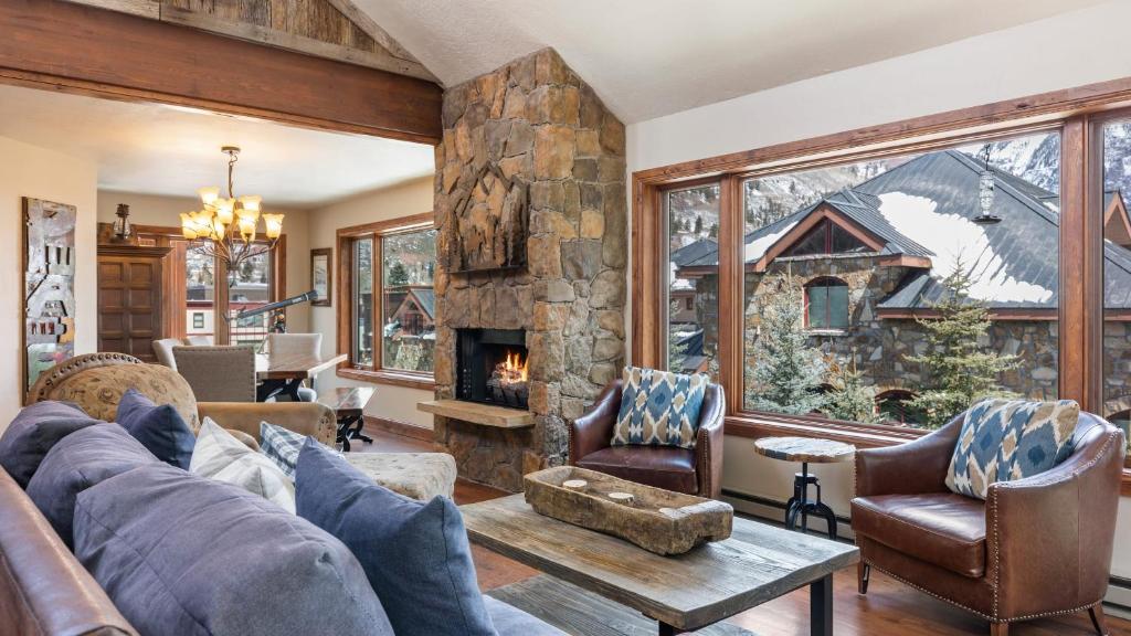 sala de estar con sofá y chimenea de piedra en Ghostriders 11 by AvantStay Top Floor Condo w Large Patio Mountain Views, en Telluride