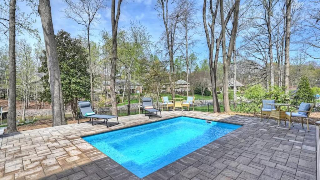 a patio with a swimming pool and chairs and a table at Porch Paradise by AvantStay New Pool Firepit in Mooresville