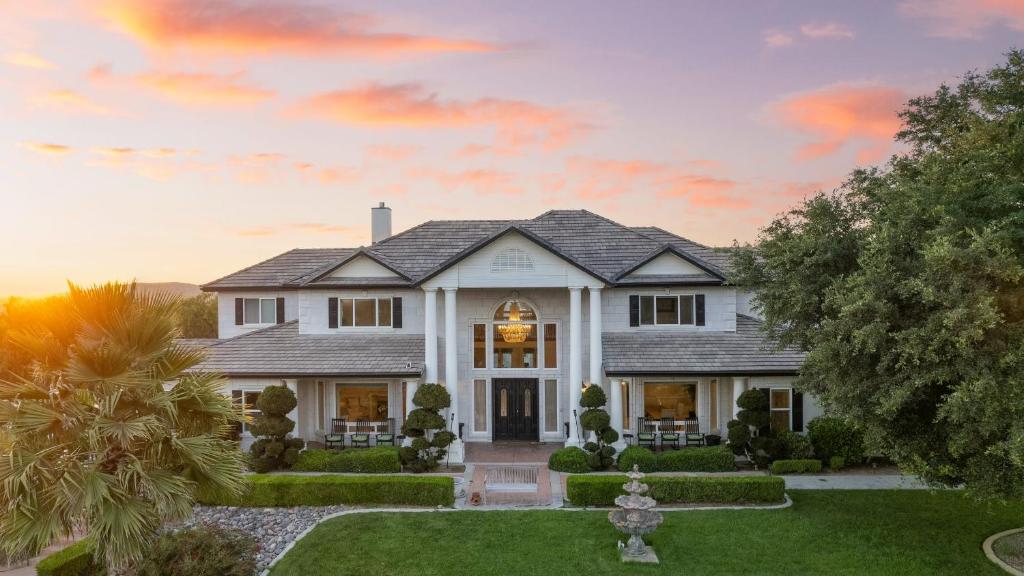 una casa blanca con una puesta de sol en el fondo en Grand Contento by AvantStay Extraordinary Estate w Pool Movie Room, en Temecula
