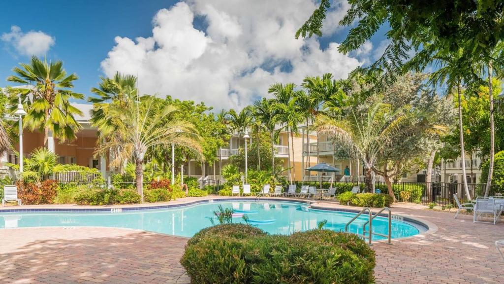 a swimming pool with palm trees in front of a building at Coral Palm by AvantStay Key West Walkable Gated Community Shared Pool in Stock Island