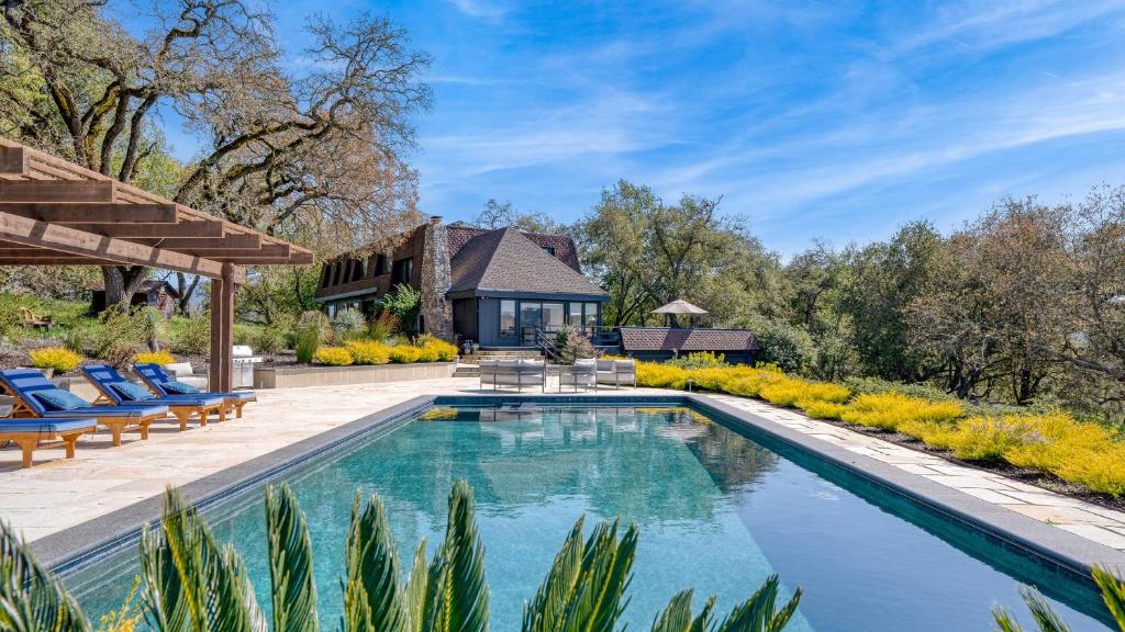 a swimming pool with chairs and a house in the background at Malvasia by AvantStay Luxe Wine Country Retreat in Santa Rosa
