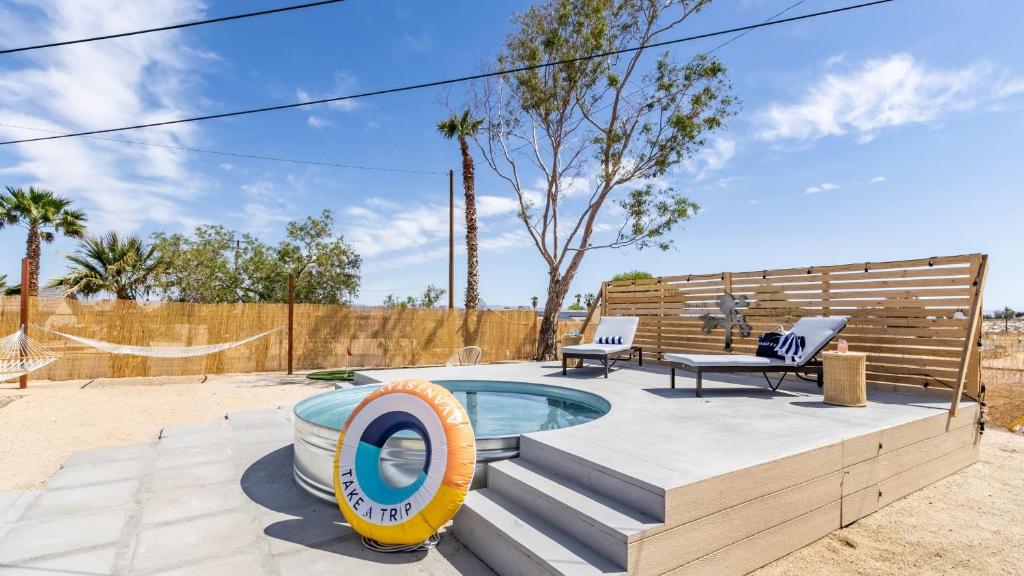 a swimming pool with a bench and a pool noodle in a yard at Carmella by AvantStay Modern JTree Home w Large Outdoor Area in Twentynine Palms