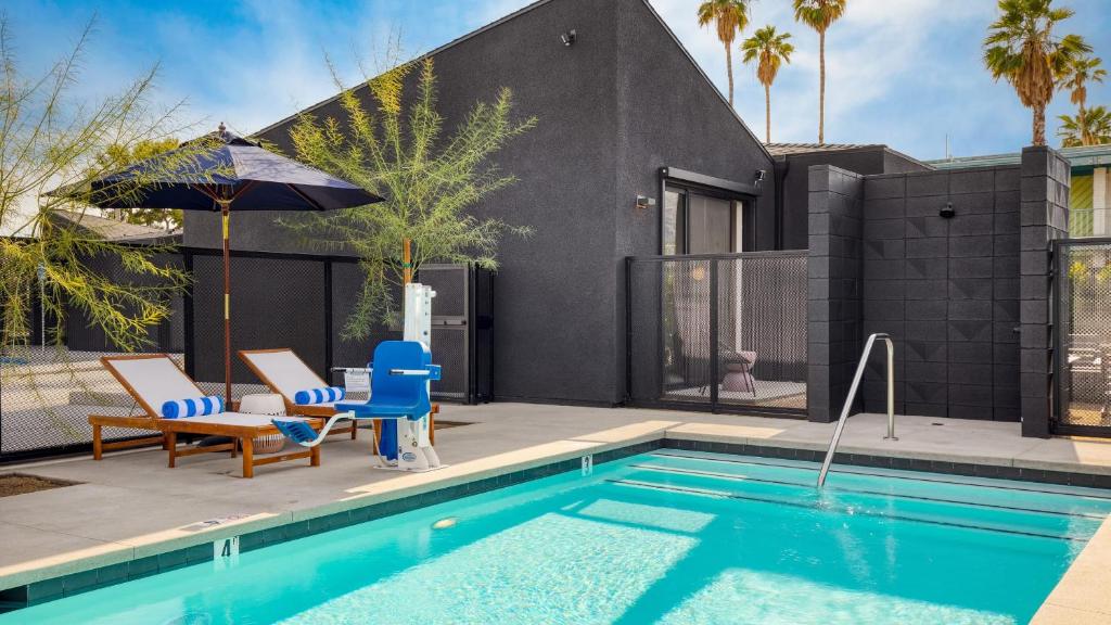 a swimming pool with two chairs and a house at Blackhaus B : 4 Bedroom Suite by AvantStay 4-Rooms in Palm Springs