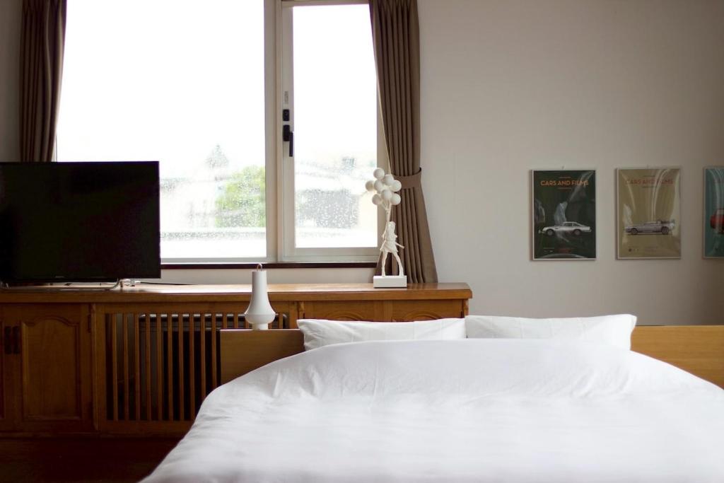 a bedroom with a white bed and a television at Seaside Inn Hokuto in Hokuto