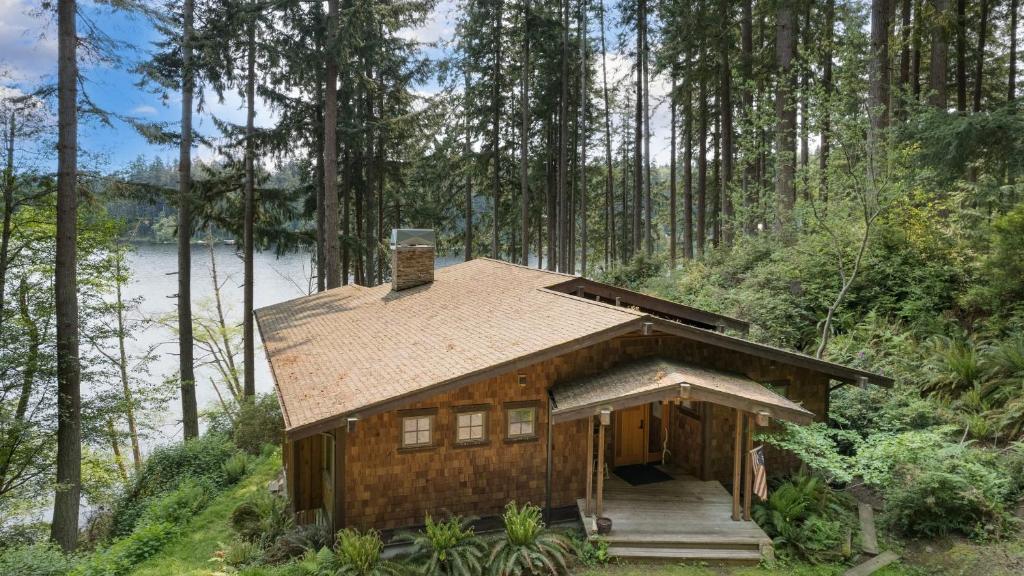 a log cabin in the woods with a lake at Goss Lake Chalet by AvantStay Lakefront w Dock Fire Pit Outdoor Dining Area in Langley