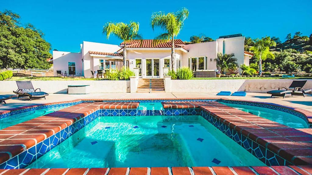 a swimming pool in front of a house at Grapevine by AvantStay Secluded 5BR Villa 4 Acres of Vineyards Avo Groves in Temecula