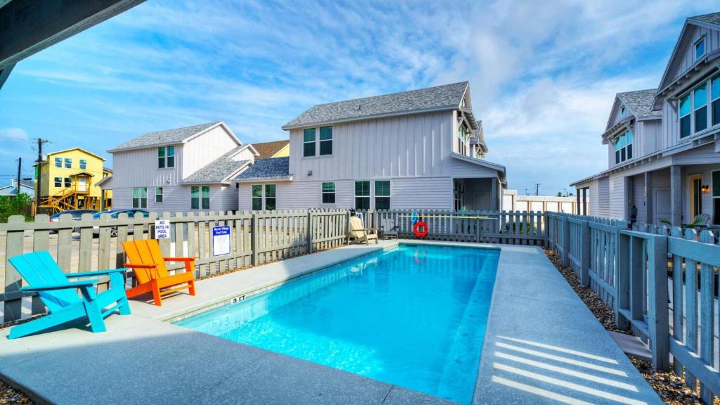 una piscina con dos sillas y una casa en Pool 1 Block to Alister Old Town Eateries Bluegrass Breeze by AvantStay, en Port Aransas