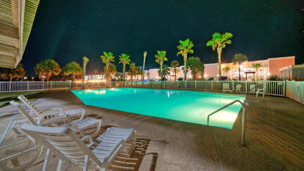 - une piscine avec des chaises et des palmiers la nuit dans l'établissement Beachfront Patio w Dune View 2 Pools Pickleball Cravin Waves by AvantStay, à Port Aransas
