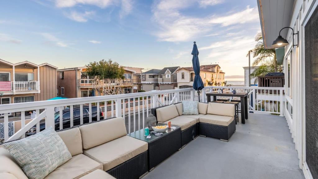 a balcony with two couches and an umbrella at Ocean Breeze II by AvantStay Steps to the Beach in Newport Beach