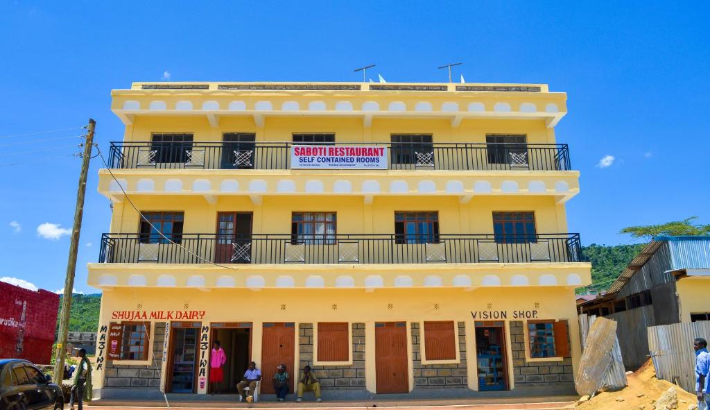 um edifício amarelo com uma varanda em cima em Saboti Hotel em Mai Mahiu