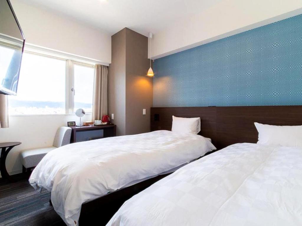 a hotel room with two beds and a blue wall at Meldia Stay Nijojo in Kyoto
