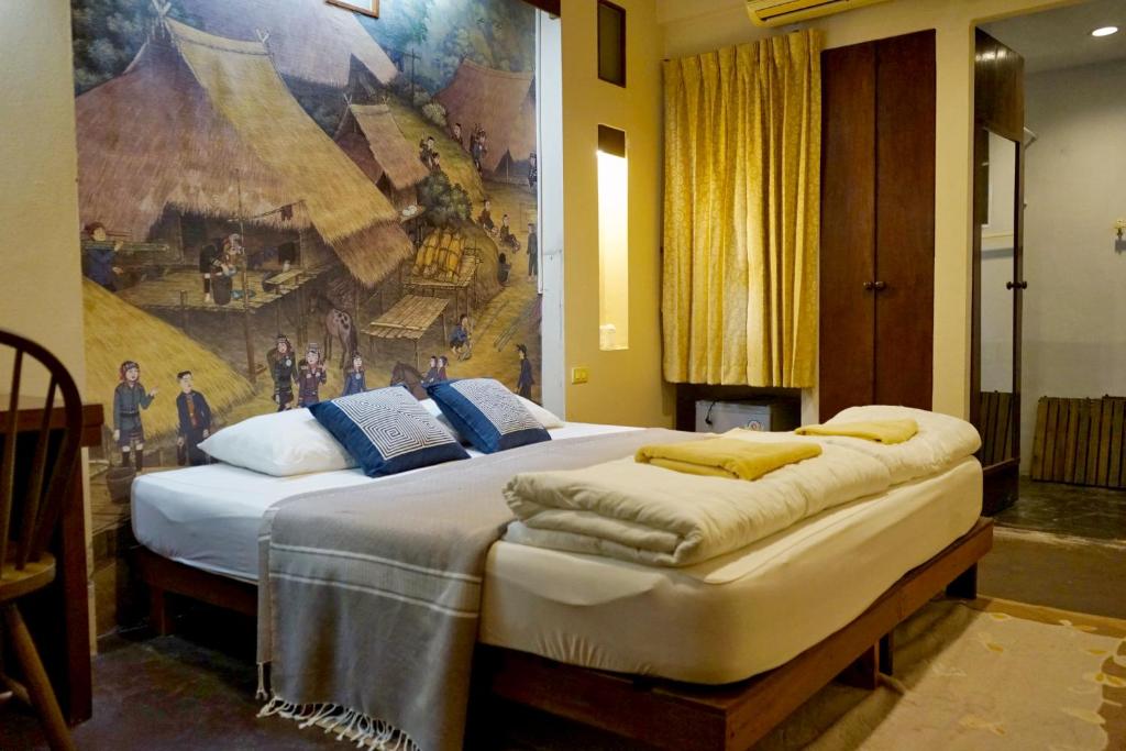 a bedroom with two beds with a painting on the wall at ComeOn Stay&Sleep in Chiang Rai