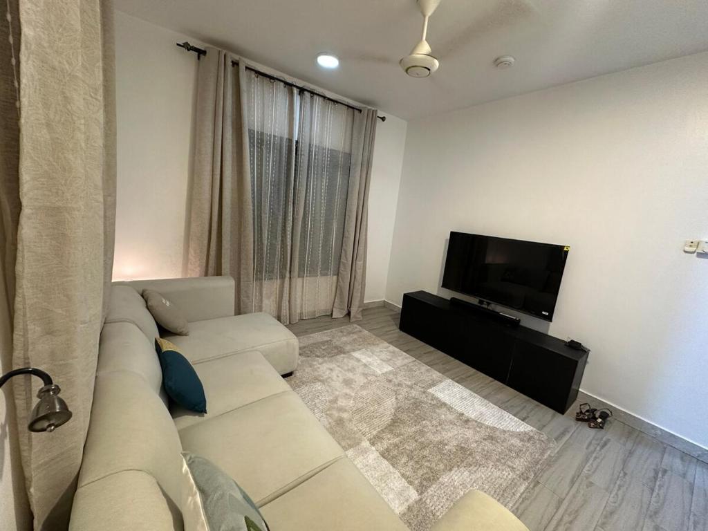 a living room with a couch and a flat screen tv at Dee s Home in Dar es Salaam