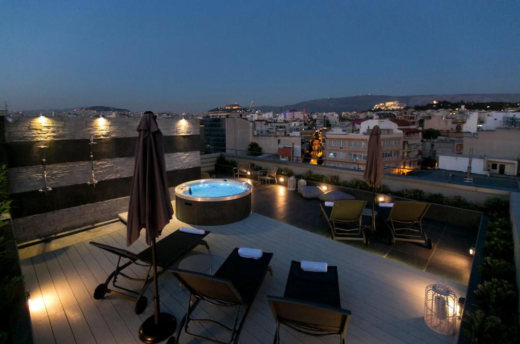 una terraza en la azotea con bañera de hidromasaje y sillas en 47 Luxury Suites, en Atenas