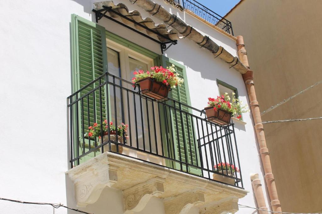 uma janela com persianas verdes e flores numa varanda em Le Stanze dell'Emiro em Sambuca di Sicilia
