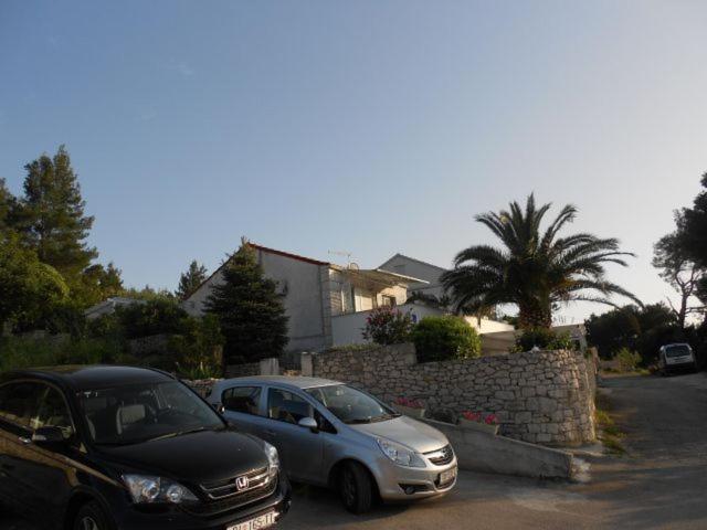 two cars parked in a parking lot next to a wall at Studio apartman Kornelija in Lumbarda