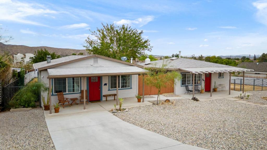 a small white house with a red door at Fable by AvantStay 2 Unique Spaces w Bowling Hot Tub Fire Pit Large Yard in Joshua Tree