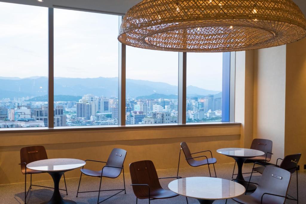 a restaurant with tables and chairs and a large window at amba Taipei Songshan in Taipei
