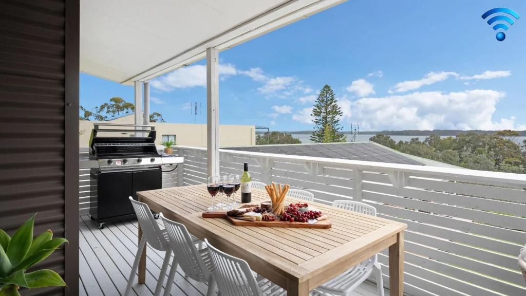 een houten tafel op een terras met een grill bij Lakeview Retreat in Culburra Beach