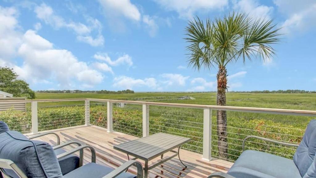 una terraza con una palmera, una mesa y sillas en 17 Marsh Island Lane by AvantStay Modern Home w Amazing Views, en Isle of Palms