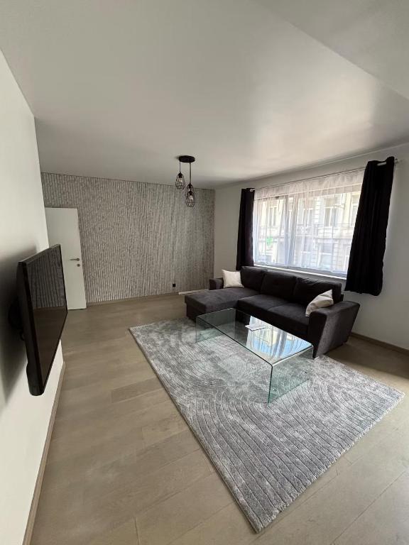 a living room with a black couch and a glass table at Stylish, modern & spacious apartment in Brussels in Brussels