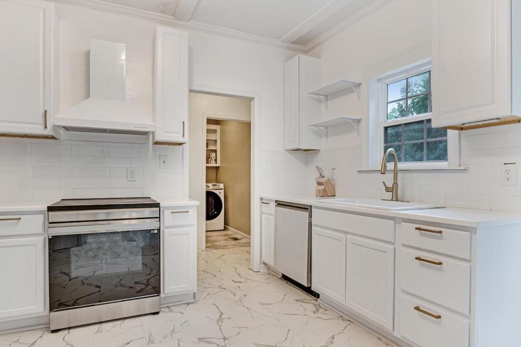 a white kitchen with a sink and a stove at Modern 1- Queen Bed On Quiet Block in Hephzibah